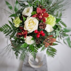 Matala kukkakimppu ruususta, kympidistä ja jaloleinikistä runsailla vihreillä ja männynhavulla.