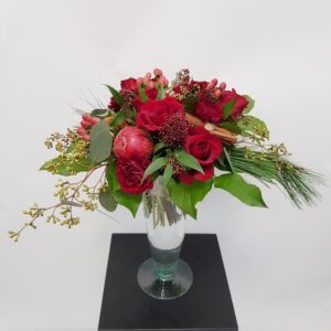 Kaunis punasävyinen kukkakimppu neilikasta, ruususta ja skimmiasta.